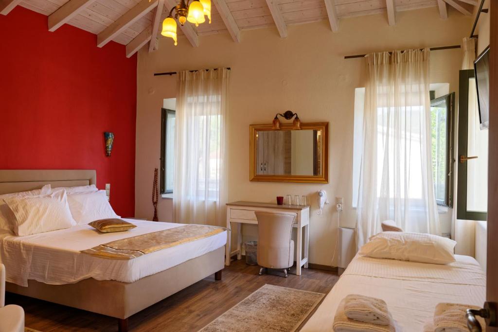 a bedroom with two beds and a desk and a mirror at Alexandra Hotel in Kaléntzion