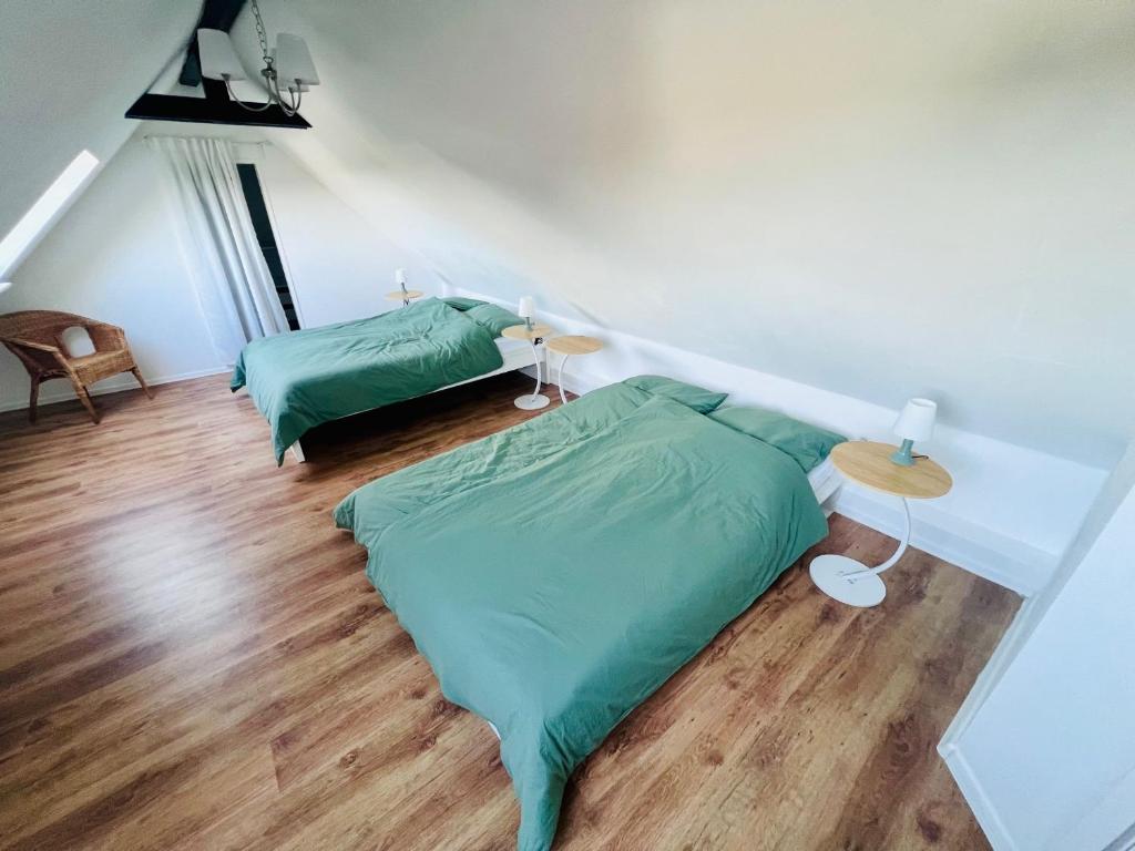 a bedroom with two green beds and a wooden floor at Charmante Maisonettewohnung im Herzen von Krefeld in Krefeld