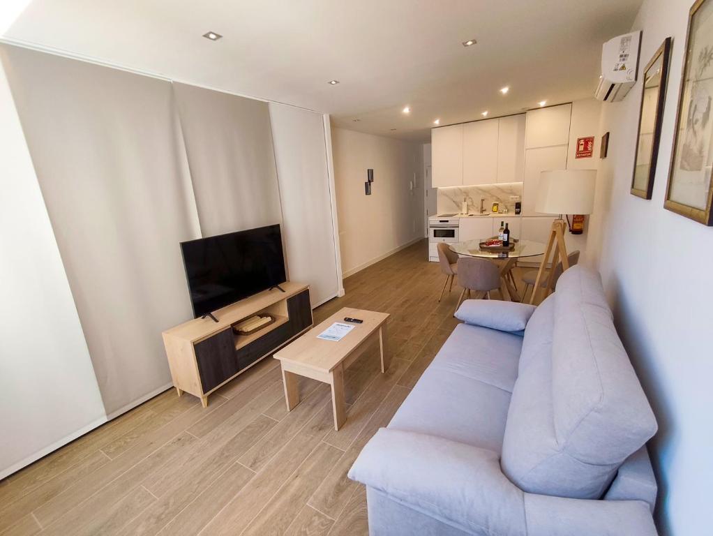 un soggiorno con un divano blu e una televisione di Apartamentos BONDELA a Madrid