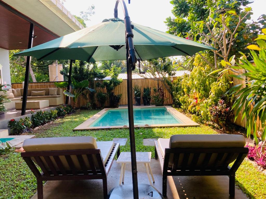 a green umbrella and two chairs next to a pool at Lanta sky pool villa in Ko Lanta