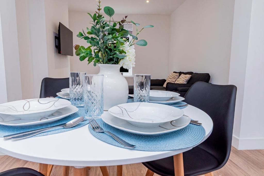 a white dining room table with plates and a vase at Stunning 3-Bedroom Home in Bletchley - Close to City Centre and Train Station - Free Private Parking - Fast Wi-Fi and Smart TV in Bletchley