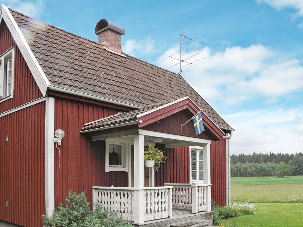 a red house with a white porch and a roof at 4 person holiday home in GULLSPÅNG-By Traum in Tattertorp
