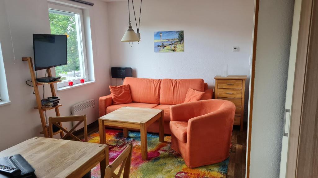 a living room with an orange couch and a table at PONTUS Ferienwohnung FEWO 3 in Zislow
