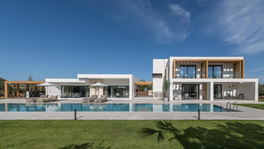 a large house with a swimming pool in front of it at Olive Sun Villa Stillness & Elegance by etouri in Kato Gouves