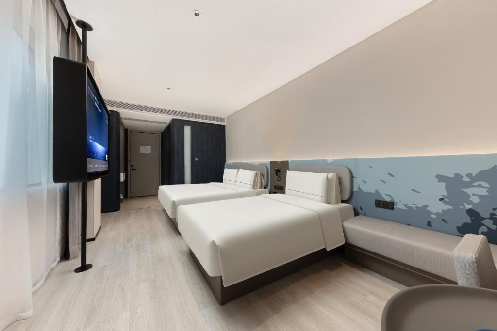Atour Hotel Shanghai Wujiaochang Huangxing Road Subway Station في شانغهاي: غرفة فندقية بسريرين وتلفزيون بشاشة مسطحة