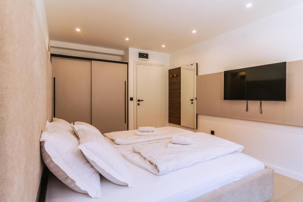 a bedroom with a bed with white pillows and a television at Luxury Rooms Terrazza Sette in Split