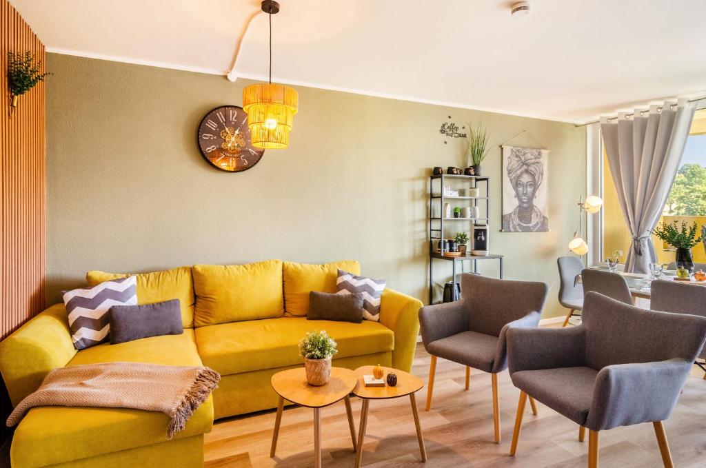 sala de estar con sofá amarillo y sillas en Superior App 238 mit Pool und Sauna, en Braunlage