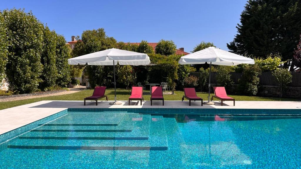 a group of chairs and umbrellas next to a swimming pool at Feel Discovery Casa Da Capela Douro Valley in Armamar