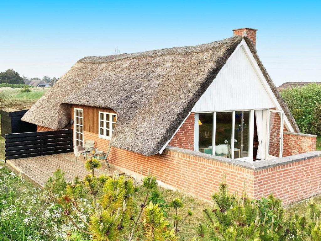a house with a thatched roof with a deck at 6 person holiday home in Ringkøbing in Ringkøbing