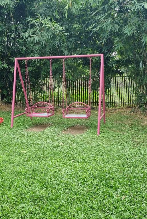 a pink swing set in a field of grass at Nishorgo Nirob Eco Resort in Sreemangal