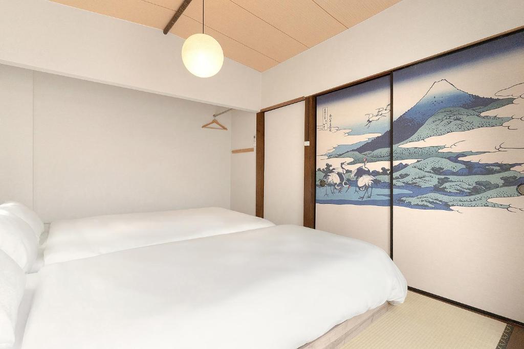 a bedroom with a white bed and a painting at YokaYado Kagoshima Chuo - Retro Style Japanese Modern Entire House with Rooftop Balcony in Kagoshima