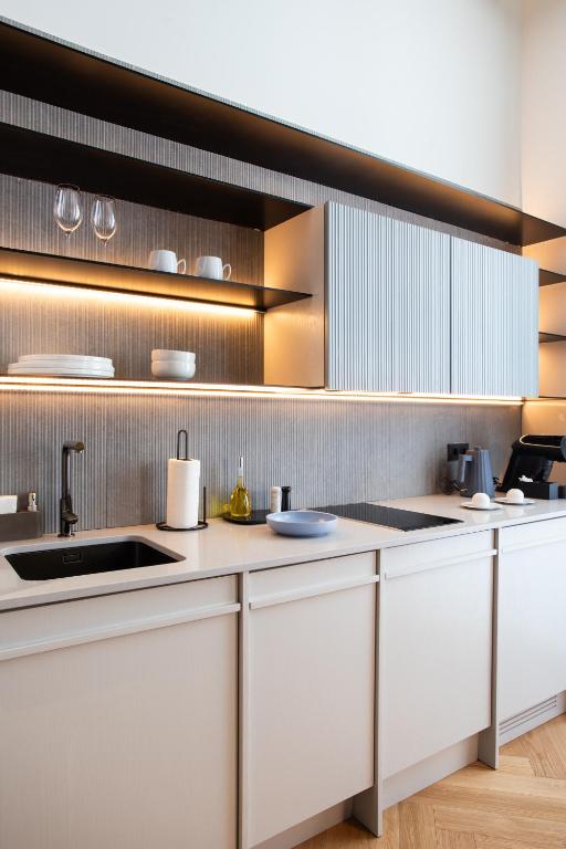 A close view of the kitchenette's sink, hob, storage and tableware.