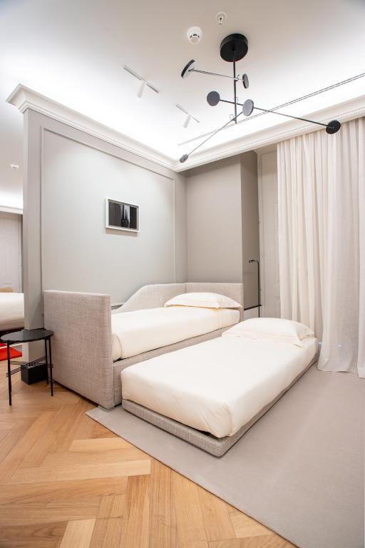 A bright multi-bed room with three single beds and a sofa-like upholstered bed frame.