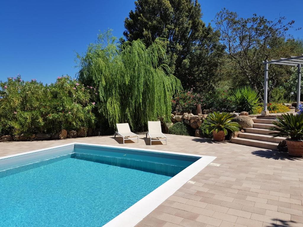 a swimming pool in a yard with two chairs and a tree at Villa Starlight vista mare La Caletta in Santa Lucia