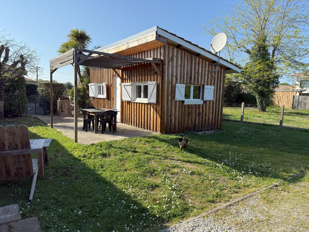 a small wooden cabin with a table in a yard at Dépendance calme Gujan-Mestras in Gujan-Mestras