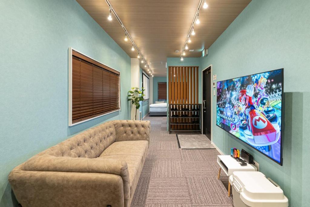 a living room with a couch and a large tv at TasoneUrbanStayOsaka 梅田北EFB2F in Wada