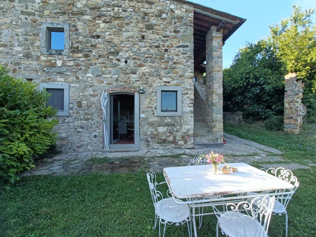 una mesa y sillas frente a una casa de piedra en Cozy Country House, en LʼOpaco