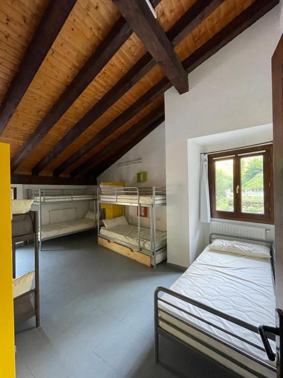 a bedroom with two bunk beds and a wooden ceiling at ALBERGUE DE LASTUR in Deba