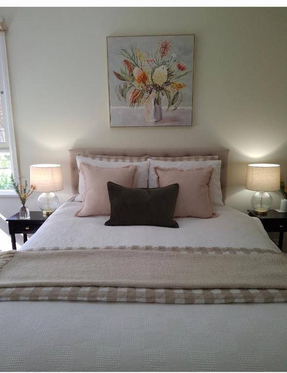 a bedroom with a large bed with pink pillows at HUNTER COTTAGE EUROA - "A great weekend escape" in Euroa