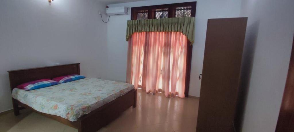 1 dormitorio con 1 cama y puerta con ventana en Nandana villa, en Sri Jayewardenepura Kotte