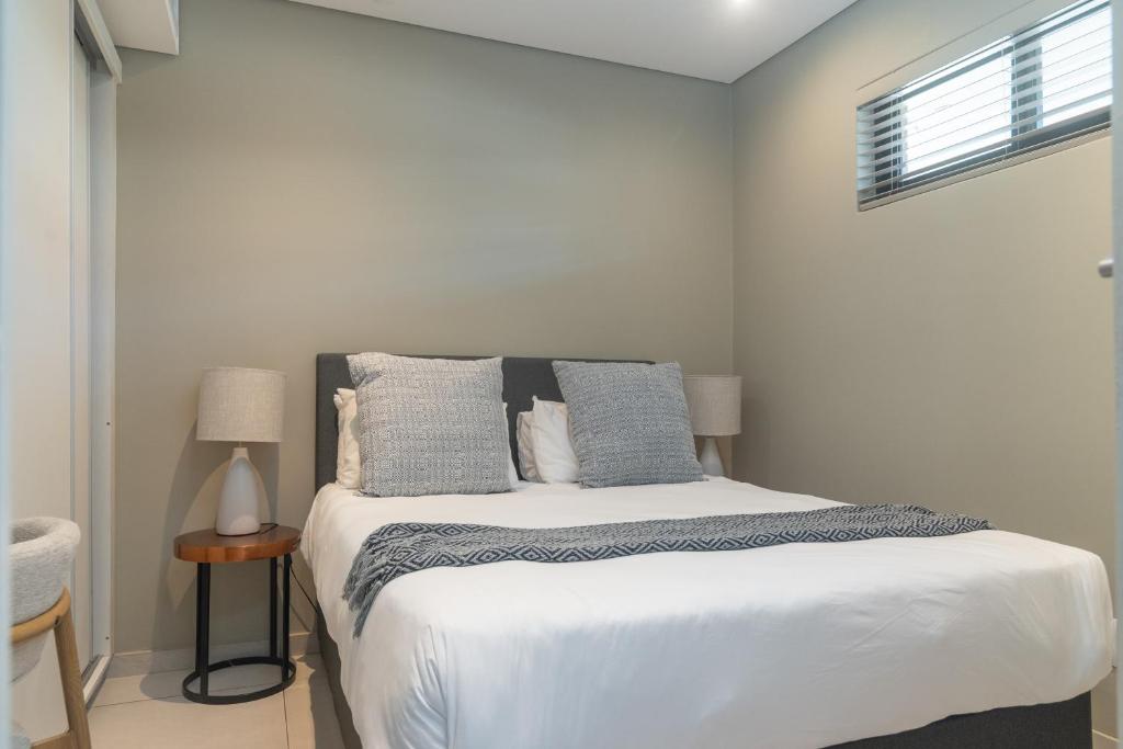 a bedroom with a bed with white sheets and blue pillows at Zimbali Suites 617 in Ballito