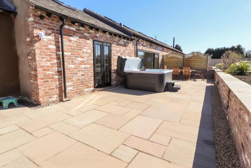 a bath tub sitting on a patio next to a brick building at The Shippon in Helsby