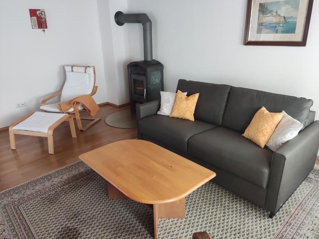 Una sala de estar con un sofá negro y una estufa de leña. en Ferienwohnung am Metzgerhof, en Bogen