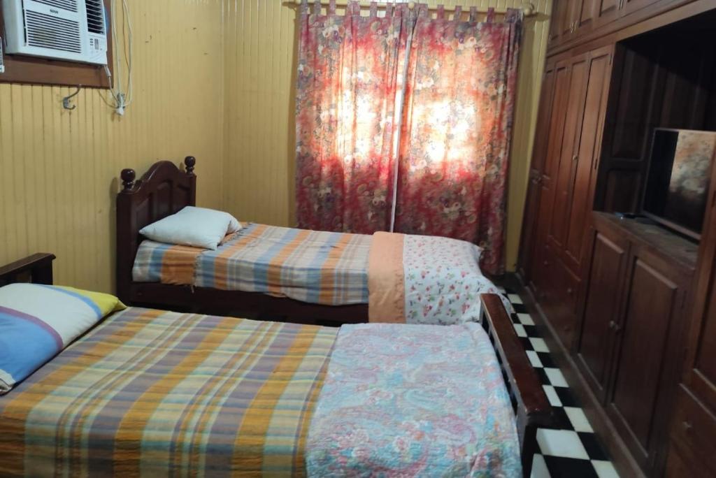 1 dormitorio con 2 camas y una ventana con cortina en Hostal Orán, en San Ramón de la Nueva Orán
