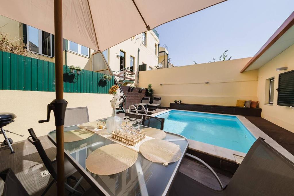 a patio with a table and an umbrella and a swimming pool at Private Pool Chiado Gem, Patio Retreat wAC in Lisbon