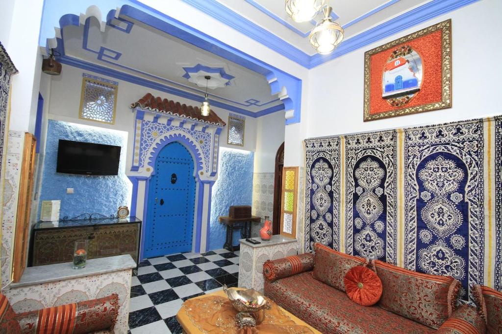 Una sala de estar con un sofá y una puerta azul. en Bab chaouen, en Chefchaouen