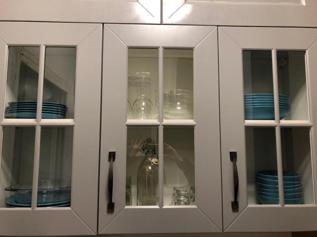 Un armario blanco con platos y cuencos en su interior. en Studio Côté Sud, en Superdevoluy