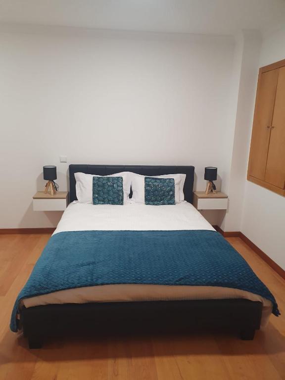 a bedroom with a large bed with a blue blanket at O AL da Baixa in Figueira da Foz