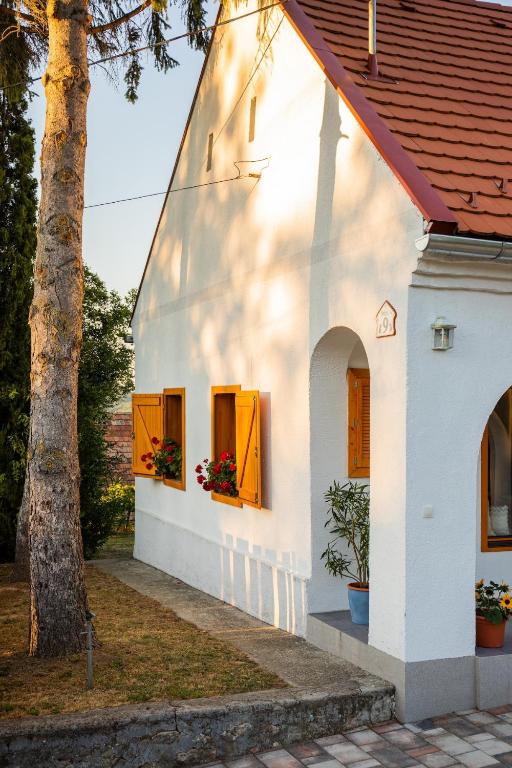 a white house with orange windows and a tree at D9 Cottage in Csesznek