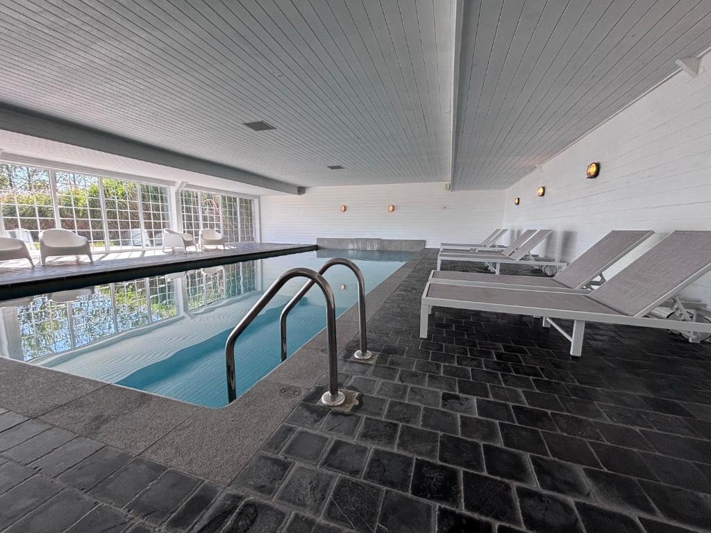 a swimming pool with lounge chairs next to a swimming pool at Kapelhoeve in De Haan