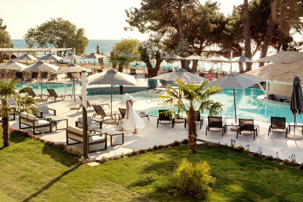 a pool with tables and chairs and umbrellas at Thassos Imperial Resort in Skala Rachoniou