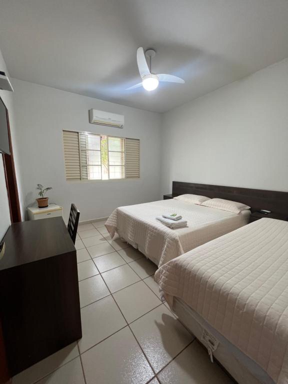 a bedroom with two beds and a ceiling fan at Hotel e Restaurante Chão Nativo in São José da Barra