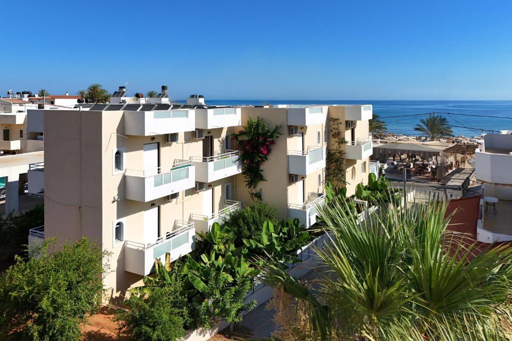 an apartment building with the ocean in the background at Smaragdine Beach Hotel in Stalís