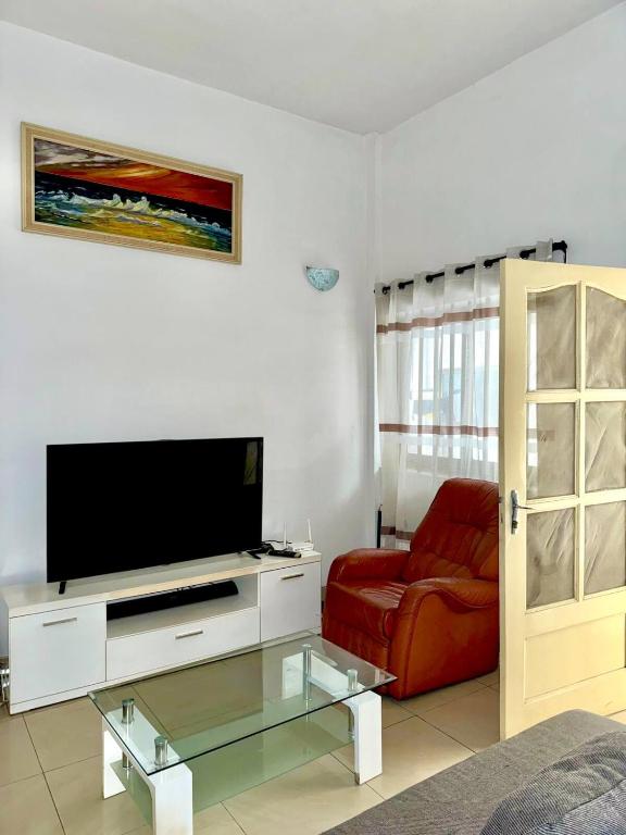 a living room with a television and a red chair at Cozy Private Apartment For 2 in Cotonou