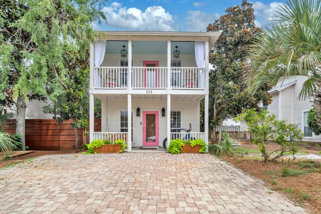 une maison blanche avec une porte rose et un balcon dans l'établissement Milo's Beach Bungalow, à Santa Rosa Beach