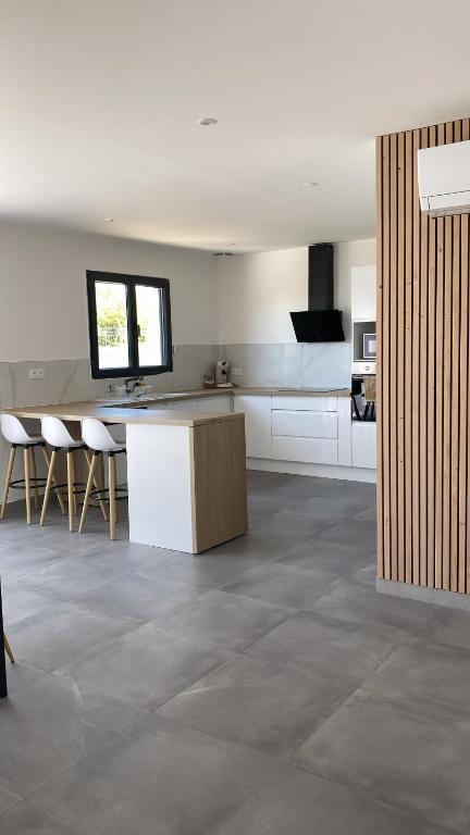 a large kitchen with white cabinets and a counter top at Jolie maison, plain-pied à Dole in Dole