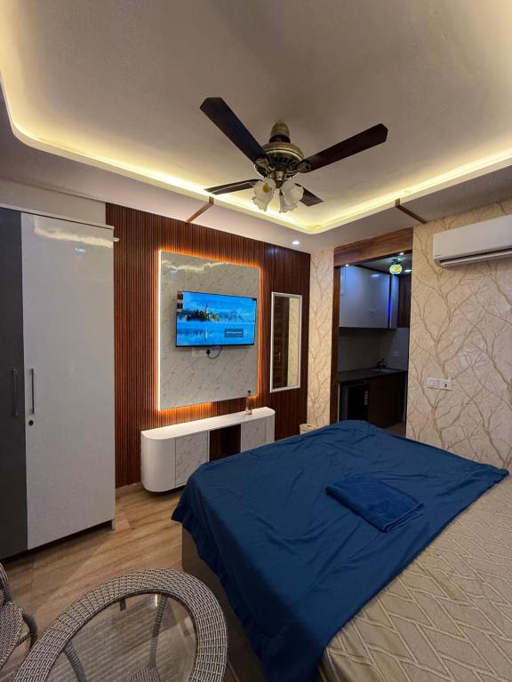 - une chambre avec un lit bleu et un ventilateur de plafond dans l'établissement Velvet Vista, à Greater Noida