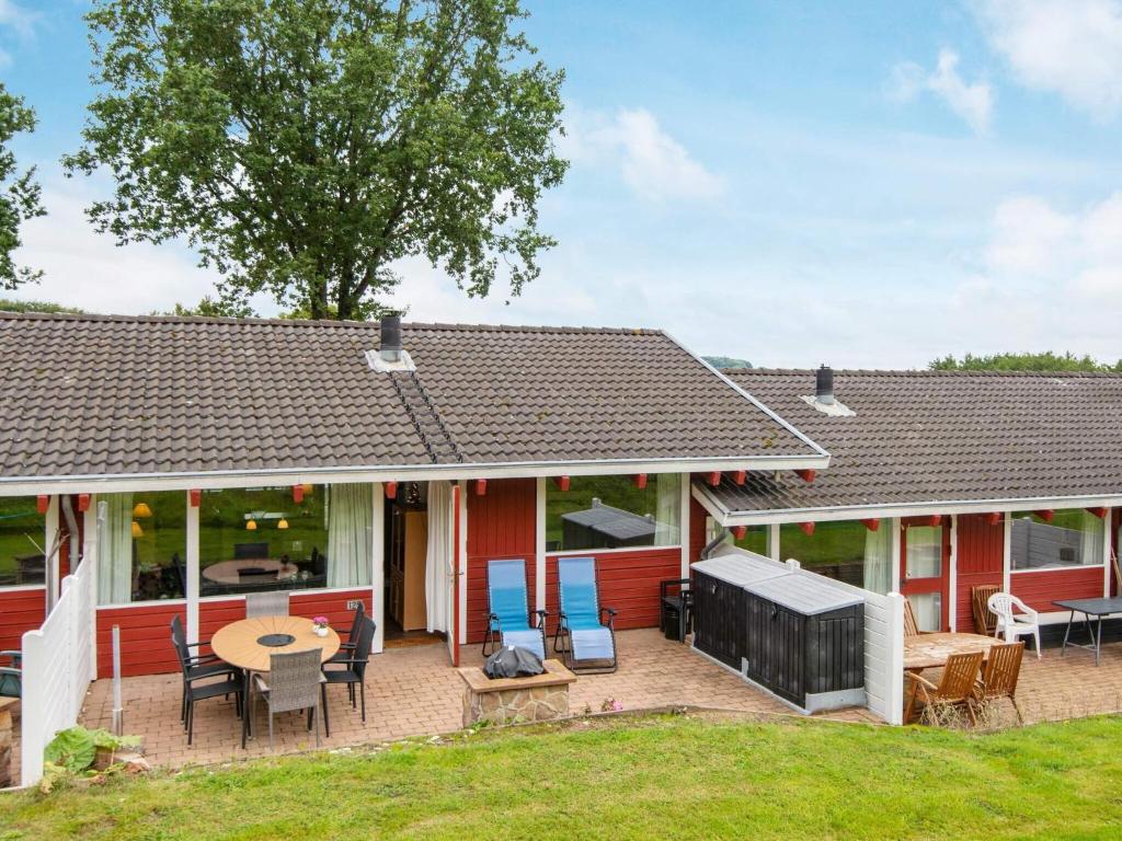 a red house with a patio with a table and chairs at 4 person holiday home in Aabenraa in Aabenraa