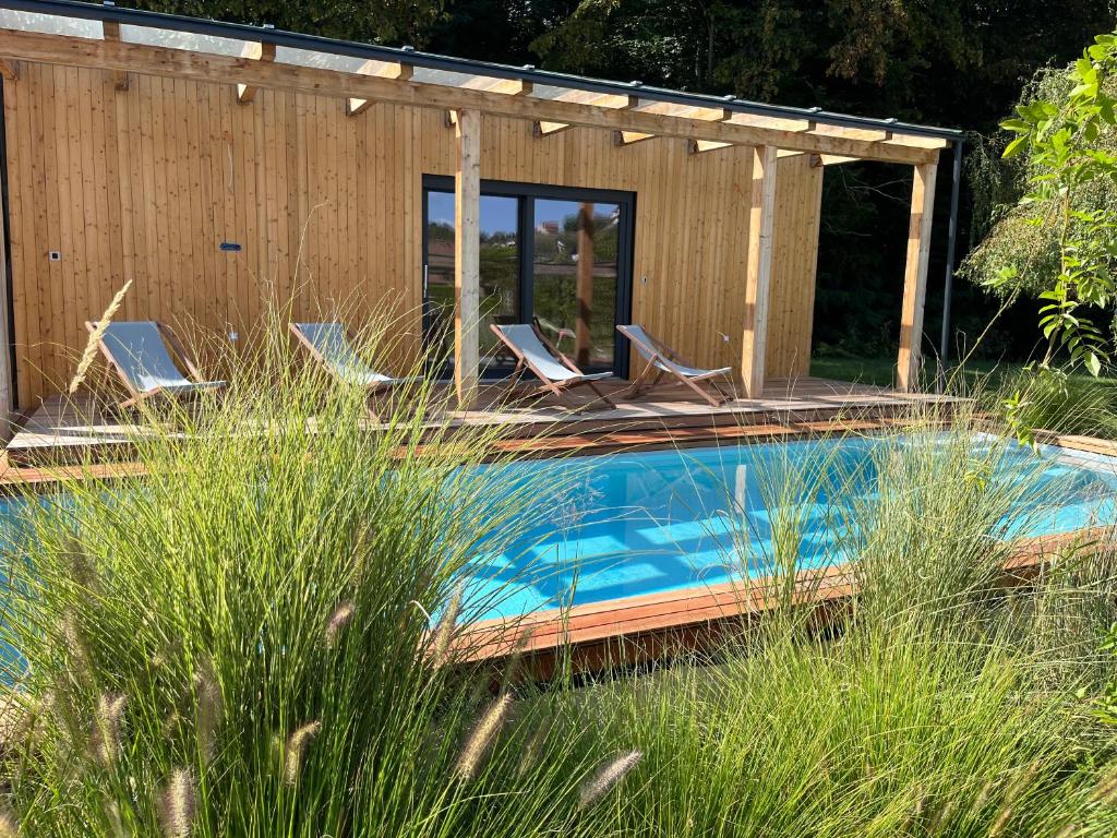 a swimming pool with chairs and a house at Country Villa with Heated Pool & Private Sauna, close to South Styrian Wine Road in Kamnica