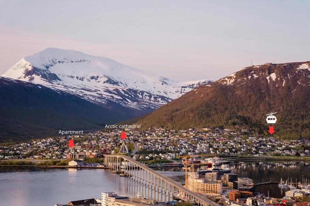 a city with a bridge over a body of water and mountains at Cozy apartment close to the city center and mountains in Tromsø