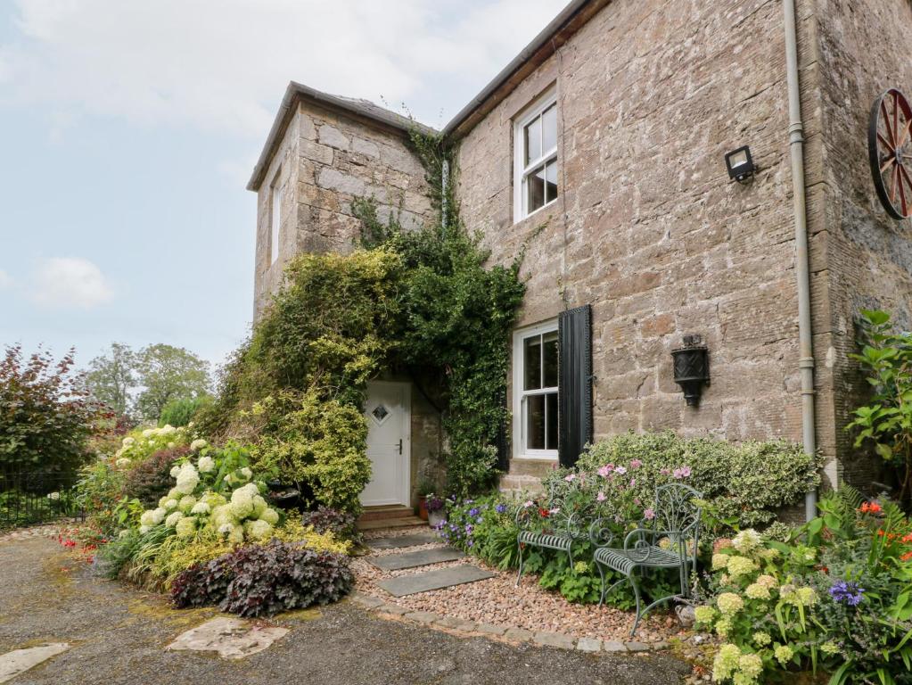 an old stone house with flowers in front of it at Balsaggart Farm in Maybole