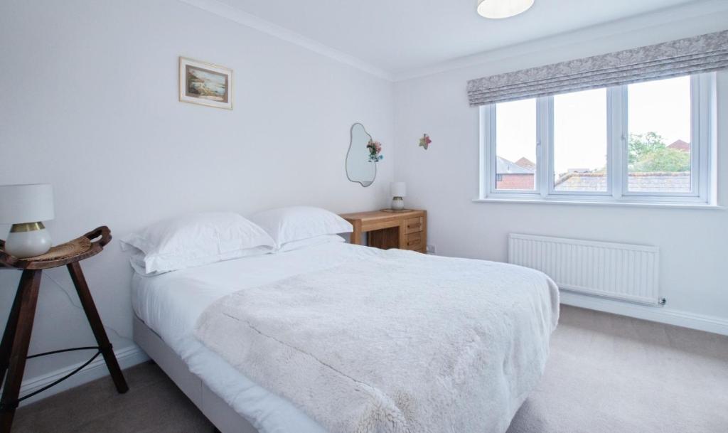 a white bedroom with a bed and a window at Catalina19 Guest home share in Poole