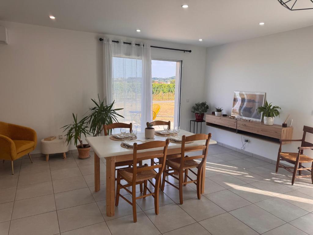 a dining room with a table and chairs and a window at Polypocket in Saint-Laurent-des-Vignes