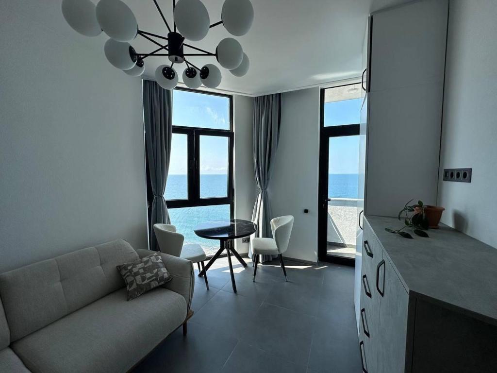 a living room with a couch and a table and some windows at 11 Апартамент с отдельной спальней in Kvariati