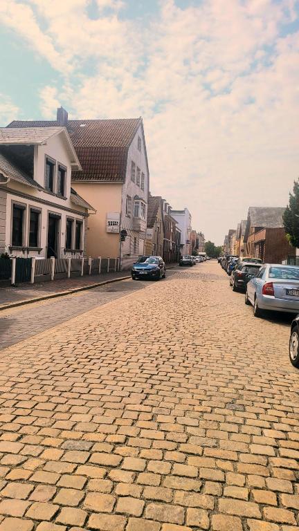 a cobblestone street with houses and cars on it at unterkunft Cuxhaven in Cuxhaven
