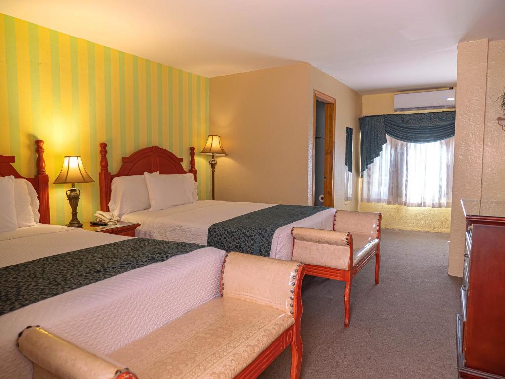 a hotel room with two beds and a chair at Boutique Hotel La Cordillera in San Pedro Sula